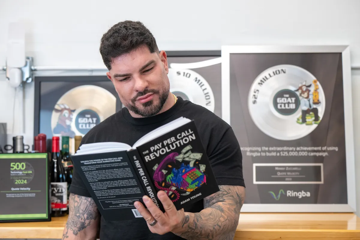 Manny Zuccarelli reading The Pay Per Call Revolution beside his GOAT Club awards